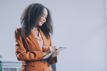 Beautiful young Asian businesswoman smiling holding a coffee mug and laptop working at the office.の写真素材