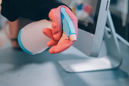 Woman cleaning computer desk in office