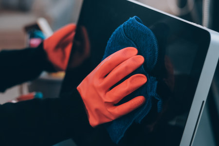 Woman cleaning computer desk in officeの写真素材