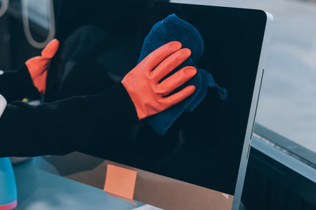 Woman cleaning computer desk in officeの写真素材