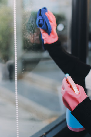An employee of a professional cleaning service in overalls washes the glass of the windows of the facade of the building. Showcase cleaning for shops and businessesの写真素材