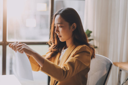 Young Asian businesswoman working on laptop computer, stressed has a headache and thinks hard from work at the office.の写真素材