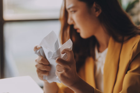 Young Asian businesswoman working on laptop computer, stressed has a headache and thinks hard from work at the office.の写真素材