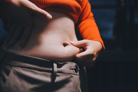 woman's hand holding belly fat