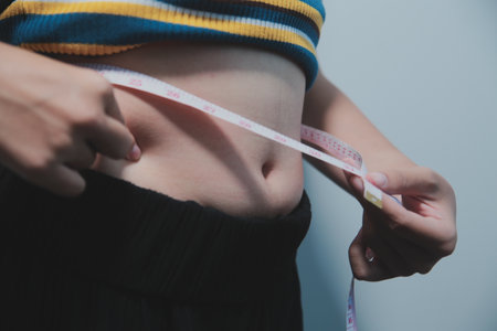 Women body fat belly. Obese woman hand holding excessive belly fat. diet lifestyle concept to reduce belly and shape up healthy stomach muscle.の写真素材