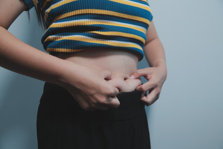 Women body fat belly. Obese woman hand holding excessive belly fat. diet lifestyle concept to reduce belly and shape up healthy stomach muscle.の写真素材