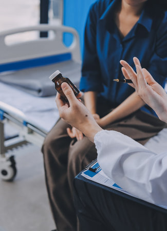 doctor consulting senior old patient filling form at consultation. Professional physician wearing white coat talking to mature woman signing medical paper at appointment visit in clinic.の写真素材