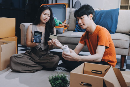 Young frustrated millennial couple sitting on couch at home, using computer and credit card. Buyers...