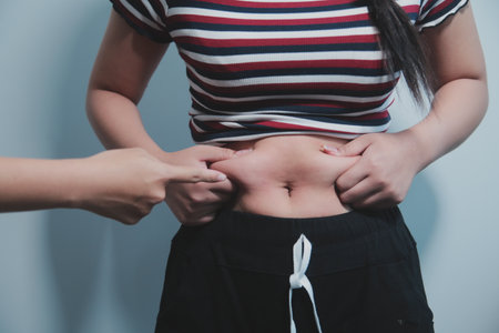 Women body fat belly. Obese woman hand holding excessive belly fat. diet lifestyle concept to reduce belly and shape up healthy stomach muscle.の写真素材