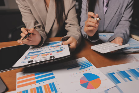 Group of confident business people point to graphs and charts to analyze market data, balance sheet, account, net profit to plan new sales strategies to increase production capacity.の写真素材