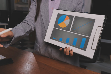 Group of confident business people point to graphs and charts to analyze market data, balance sheet, account, net profit to plan new sales strategies to increase production capacity.の写真素材