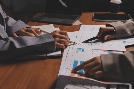 Group of confident business people point to graphs and charts to analyze market data, balance sheet, account, net profit to plan new sales strategies to increase production capacity.の写真素材