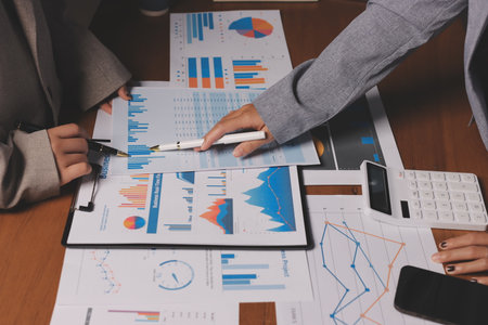 Group of confident business people point to graphs and charts to analyze market data, balance sheet, account, net profit to plan new sales strategies to increase production capacity.の写真素材