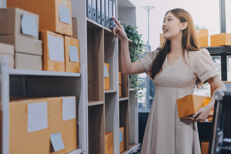 Asian SME business women use laptop computer checking customer order online shipping boxes at home....