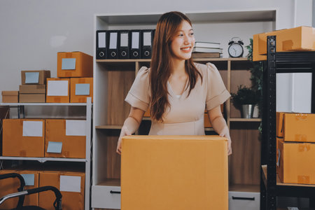 Asian SME business women use laptop computer checking customer order online shipping boxes at home....