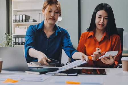 Entrepreneur Asian businessman and businesswoman discussing new business project in tablet in modern Meeting In Modern Office, Asian business casual concept.の写真素材