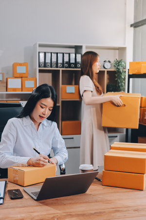Asian SME business women use laptop computer checking customer order online shipping boxes at home. Starting Small business entrepreneur SME freelance. Online business, Work at home concept.の写真素材