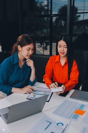 Entrepreneur Asian businessman and businesswoman discussing new business project in tablet in modern Meeting In Modern Office, Asian business casual concept.の写真素材
