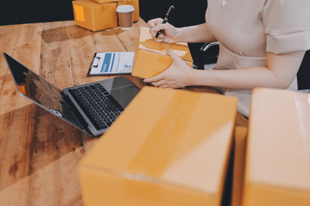 Startup SME small business entrepreneur of freelance Asian woman using a laptop with box Cheerful...