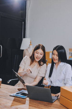 Startup SME small business entrepreneur of freelance Asian woman using a laptop with box Cheerful success Asian woman her hand lifts up online marketing packaging box and delivery SME idea conceptの写真素材