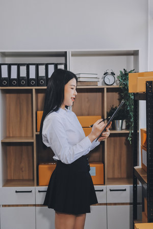 Startup SME small business entrepreneur of freelance Asian woman using a laptop with box Cheerful success Asian woman her hand lifts up online marketing packaging box and delivery SME idea conceptの写真素材