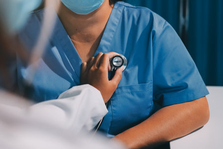 Homecare nursing service and elderly people cardiology healthcare. Close up of young hispanic female doctor nurse check mature caucasian man patient heartbeat using stethoscope during visitの写真素材