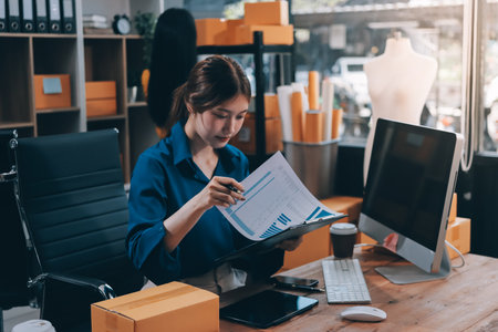Asian business women use laptop computer checking customer order online shipping boxes at home. Starting Small business entrepreneur SME freelance. Online business, Work at home concept.の写真素材