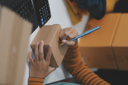 vlogger, blogger small SME business asian woman using mobile phone video call for sell clothes live stream selling online, show product present detail at home office, entrepreneur ecommerceの写真素材