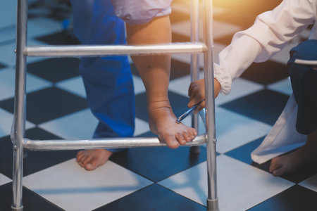 Asian professional friendly female nurse in blue hospital uniform helping supporting physical therapy senior old pensioner injury woman patient walking via four legs walker.の写真素材