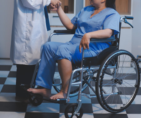 Asian female nurse in blue hospital uniform helping supporting physical therapy senior old pensioner woman patient walking via four legs walker.の写真素材