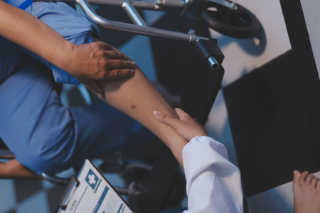 Asian professional female nurse in blue hospital uniform helping supporting physical therapy senior old pensioner woman patient walking via four legs walker.の写真素材