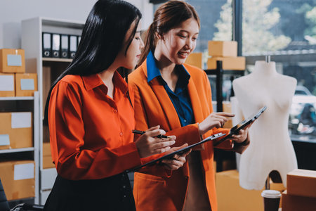 Fashion blogger concept, Young Asian women selling clothes on video streaming.Startup small business SME, using smartphone or tablet taking receive and checking in officeの写真素材