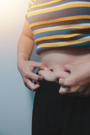 Women body fat belly. Obese woman hand holding excessive belly fat. diet lifestyle concept to reduce belly and shape up healthy stomach muscle.の写真素材