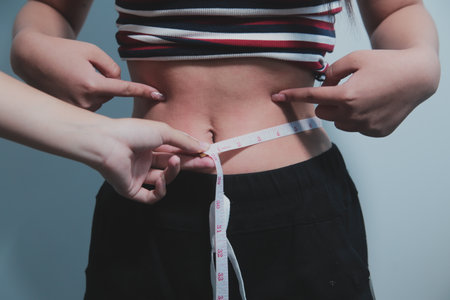 Women body fat belly. Obese woman hand holding excessive belly fat. diet lifestyle concept to reduce belly and shape up healthy stomach muscle.の写真素材