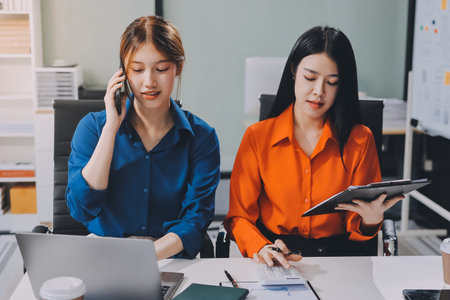 Entrepreneur Asian businessman and businesswoman discussing new business project in tablet in modern Meeting In Modern Office, Asian business casual concept.の写真素材