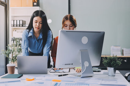 Entrepreneur Asian businessman and businesswoman discussing new business project in tablet in modern Meeting In Modern Office, Asian business casual concept.の写真素材