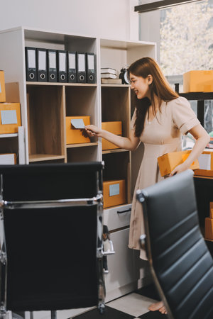 Asian SME business women use laptop computer checking customer order online shipping boxes at home. Starting Small business entrepreneur SME freelance. Online business, Work at home concept.の写真素材