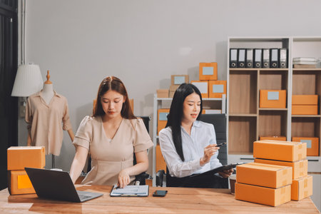Startup SME small business entrepreneur of freelance Asian woman using a laptop with box Cheerful success Asian woman her hand lifts up online marketing packaging box and delivery SME idea conceptの写真素材