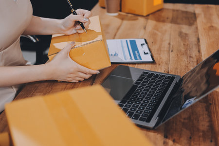 Startup SME small business entrepreneur of freelance Asian woman using a laptop with box Cheerful success Asian woman her hand lifts up online marketing packaging box and delivery SME idea conceptの写真素材