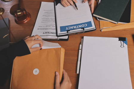 Business woman and lawyers discussing contract papers with brass scale on wooden desk in office. Law, legal services, advice, Justice and real estate concept.の写真素材