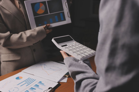 Group of confident business people point to graphs and charts to analyze market data, balance sheet, account, net profit to plan new sales strategies to increase production capacity.の写真素材