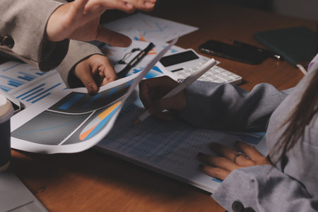Group of confident business people point to graphs and charts to analyze market data, balance sheet, account, net profit to plan new sales strategies to increase production capacity.の写真素材
