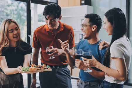 Asian office colleagues and friends enjoy a daytime BBQ with pizza and beer, creating a lively atmosphere filled with joy.の写真素材
