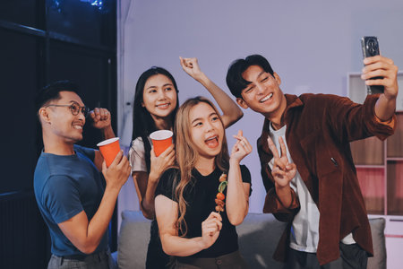 Happy young friends group having lunch at home. Asia family party eating pizza and laughing enjoying meal while sitting at dining table together at house. Celebration holiday and togetherness.の写真素材