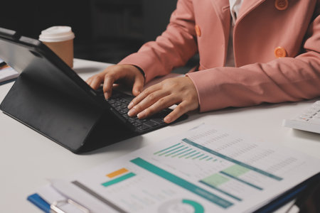 Cropped image of professional businesswoman working at her office via laptop, young female manager using portable computer device while sitting at modern loft, flare light, work process conceptの写真素材