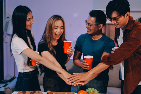 Happy young friends group having lunch at home. Asia family party eating pizza and laughing enjoying meal while sitting at dining table together at house. Celebration holiday and togetherness.の写真素材