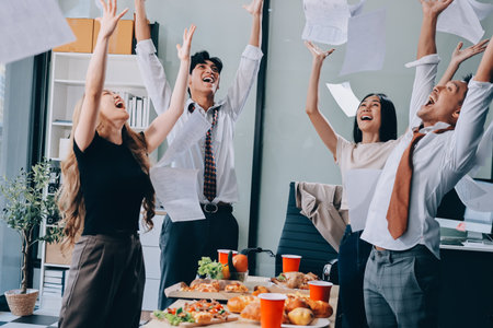 Asian office colleagues and friends enjoy a daytime BBQ with pizza and beer, celebrating and cheering for their favorite soccer team, creating a lively atmosphere filled with joy.の写真素材