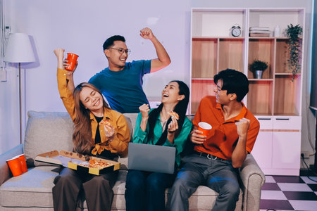 Happy young friends group having lunch at home. Asia family party eating pizza and laughing enjoying meal while sitting at dining table together at house. Celebration holiday and togetherness.の写真素材