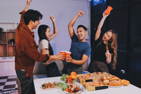Happy young friends group having lunch at home. Asia family party eating pizza and laughing enjoying meal while sitting at dining table together at house. Celebration holiday and togetherness.の写真素材