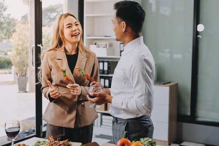 Asian office colleagues and friends enjoy a daytime BBQ with pizza and beer, creating a lively atmosphere filled with joy.の写真素材